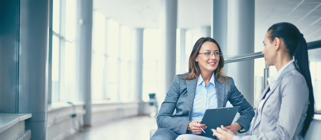 cheerful-businesswoman-talking-her-workmate