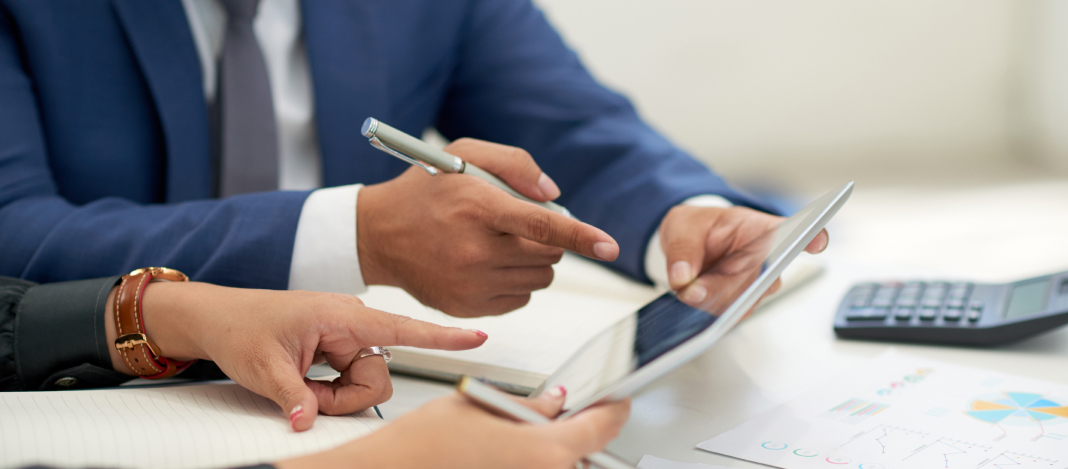 unrecognizable-business-people-sitting-meeting-with-charts-looking-pointing-tablet